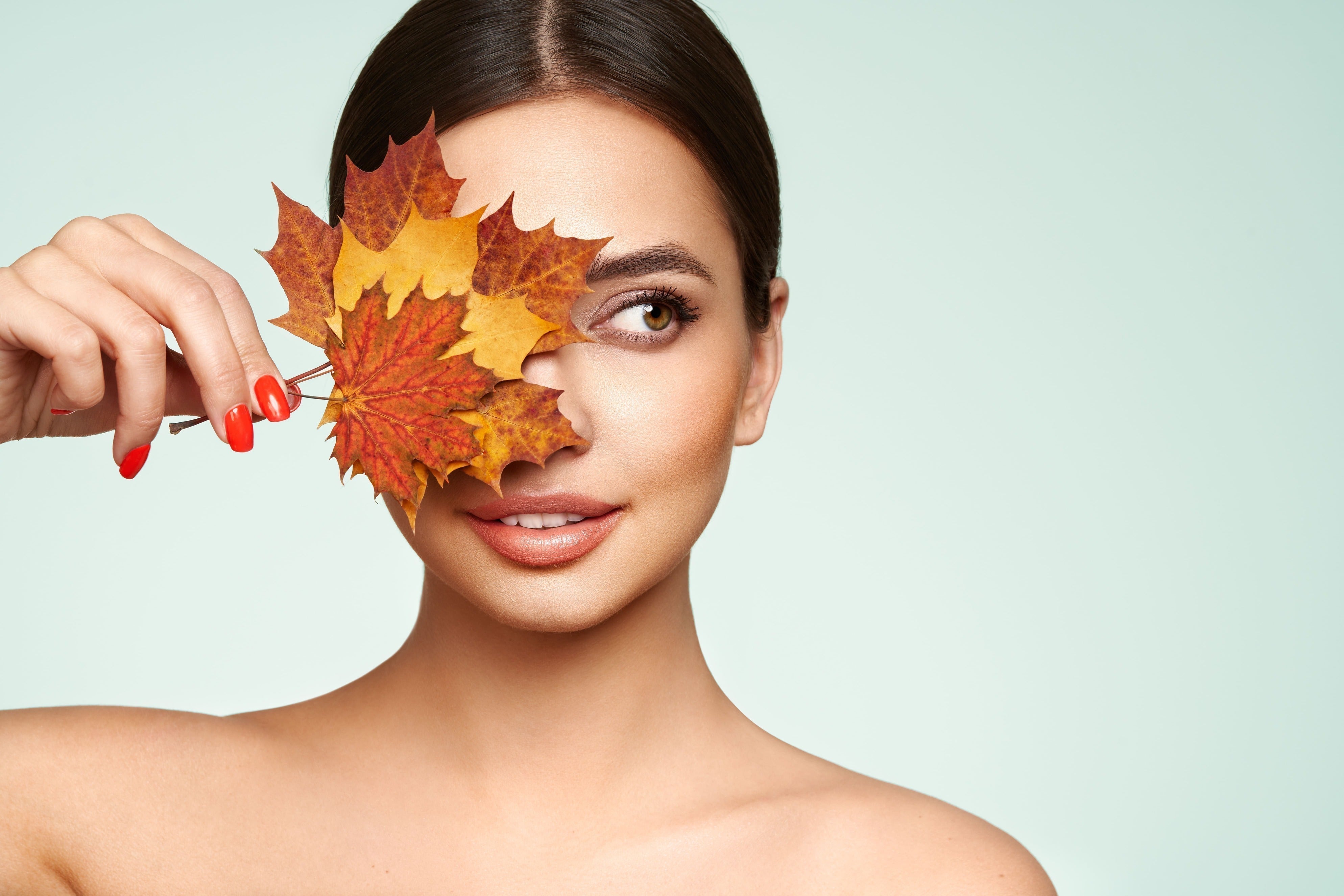 Woman with autumn leafs. Healthy clean fresh skin natural make up beauty eyes and red nails by Oleg Gekman